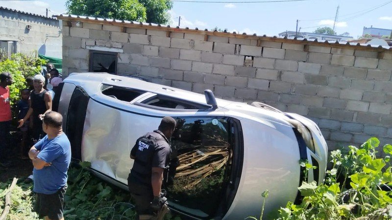 Silver Toyota Corolla on its side after crashing into a house