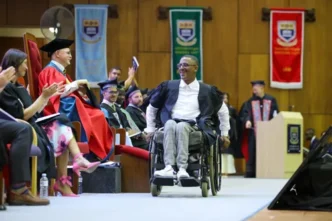 Riyaadh Kader in his wheelchair, holding his LLB certificate