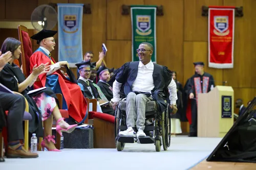 Riyaadh Kader in his wheelchair, holding his LLB certificate