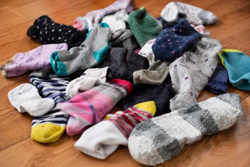 A pile of lonely socks with a pair of scissors and a needle nearby